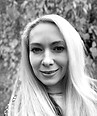 Black and white portrait of a smiling woman with long blonde hair.