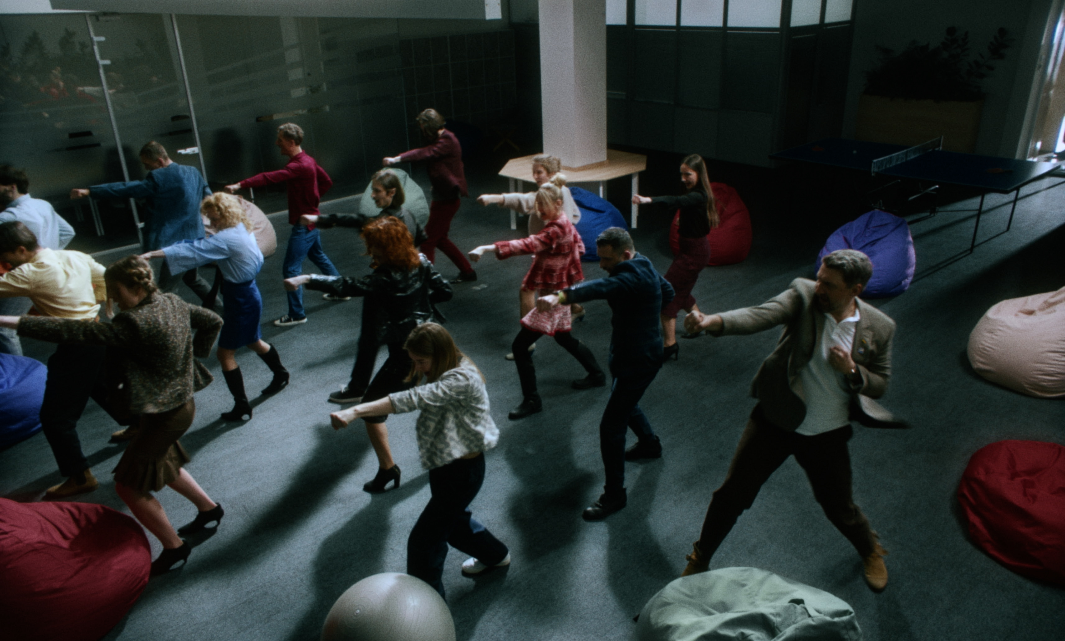 Employees perform a synchronized exercise during a corporate training session — a still from Kira’s