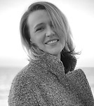 Black and white portrait of a smiling woman in a textured coat.